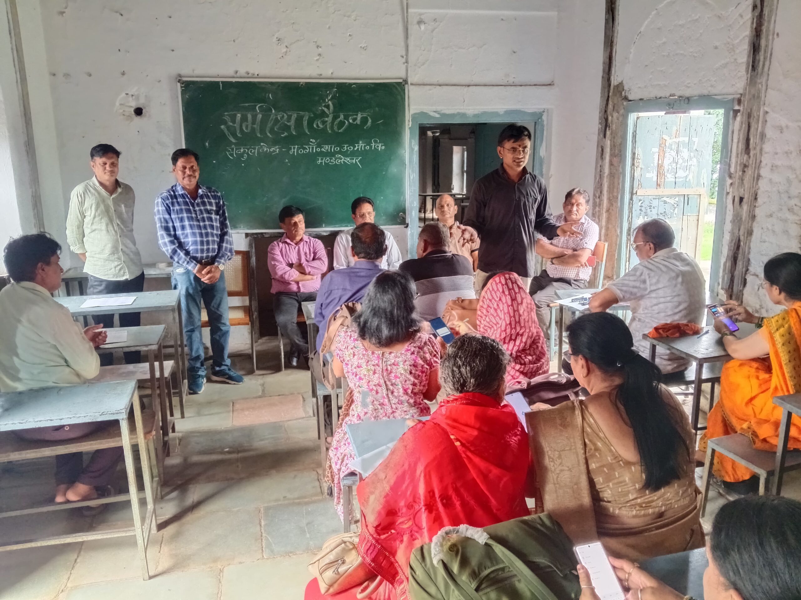 Alt Text (English): Education officials and school representatives attend a meeting in Mandleshwar under the Ullas Nav Bharat Literacy Programme to plan literacy classes for illiterate youth and elderly people through Sakshar Saathi volunteers